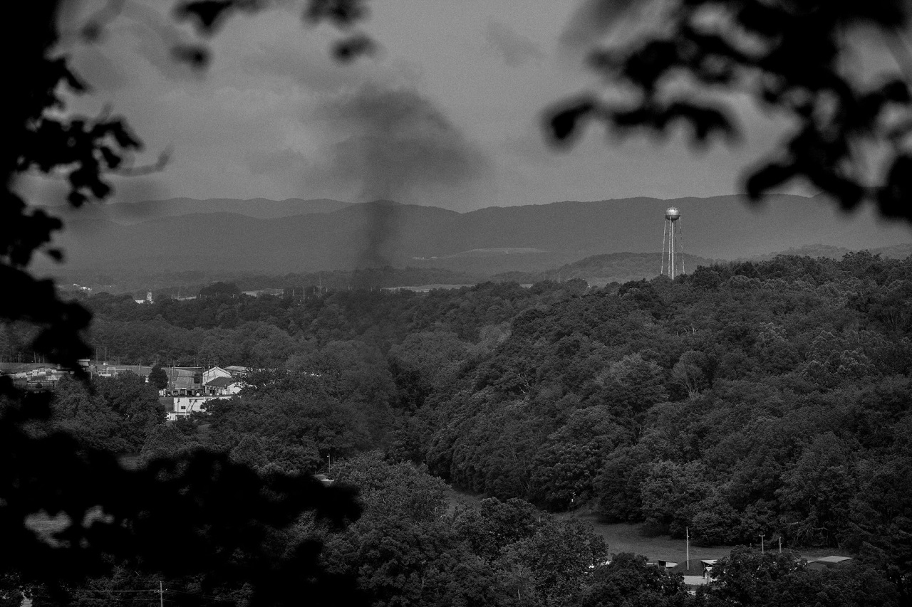 Cluster of trees at Radford Army Ammunition Plant in Virginia, with a black smoke rising in the air