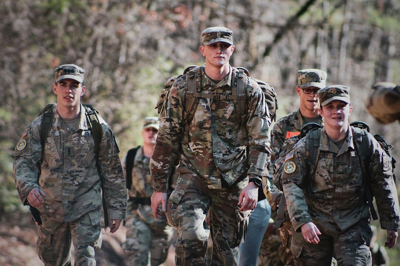 A group of U.S. soldiers in their camouflage uniform and carrying a backpack while walking on a field
